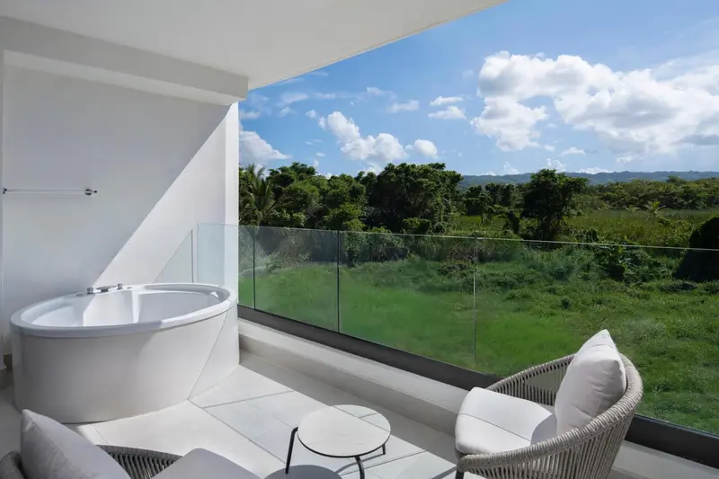 Une baignoire sur une terrasse avec vue sur un paysage verdoyant.