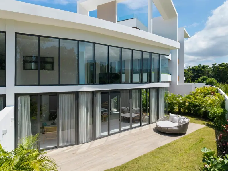 Façade moderne d'un bâtiment blanc avec de larges baies vitrées et une terrasse aménagée.