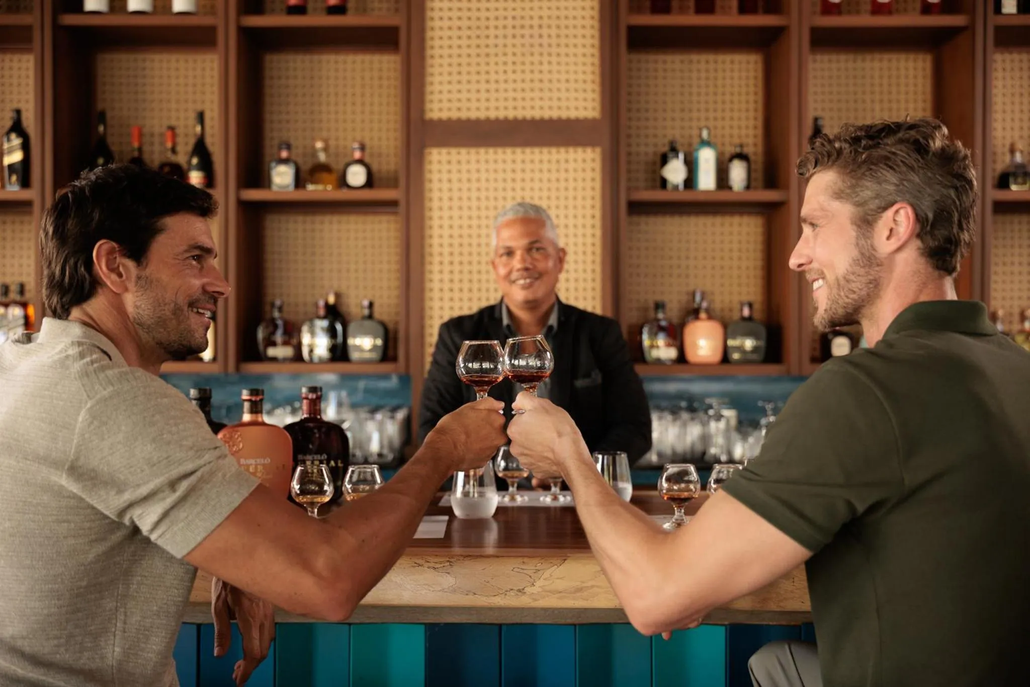 Deux hommes trinquant avec des verres de vin au comptoir d'un bar.