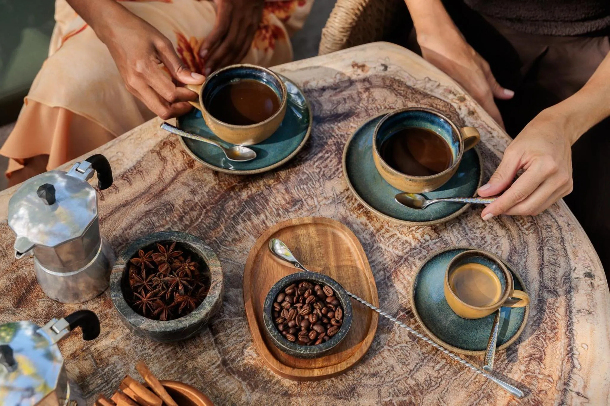 Une table en bois présente des tasses de café et des épices.