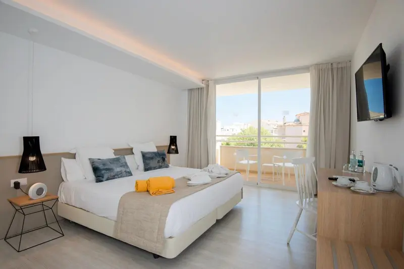 Chambre lumineuse avec un grand lit et un accès à un balcon.