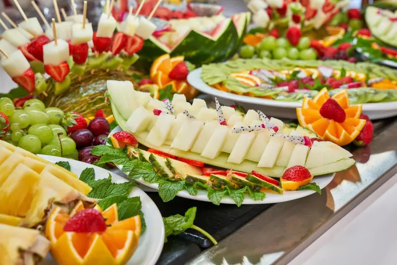 Présentation colorée de fruits frais coupés en morceaux et disposés sur un buffet.
