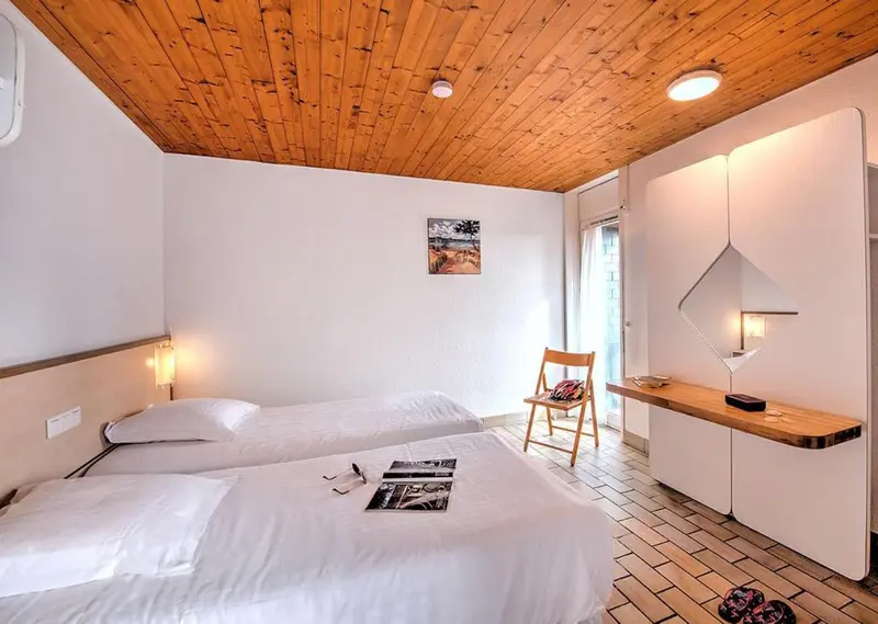 Une chambre lumineuse avec deux lits simples et un bureau.