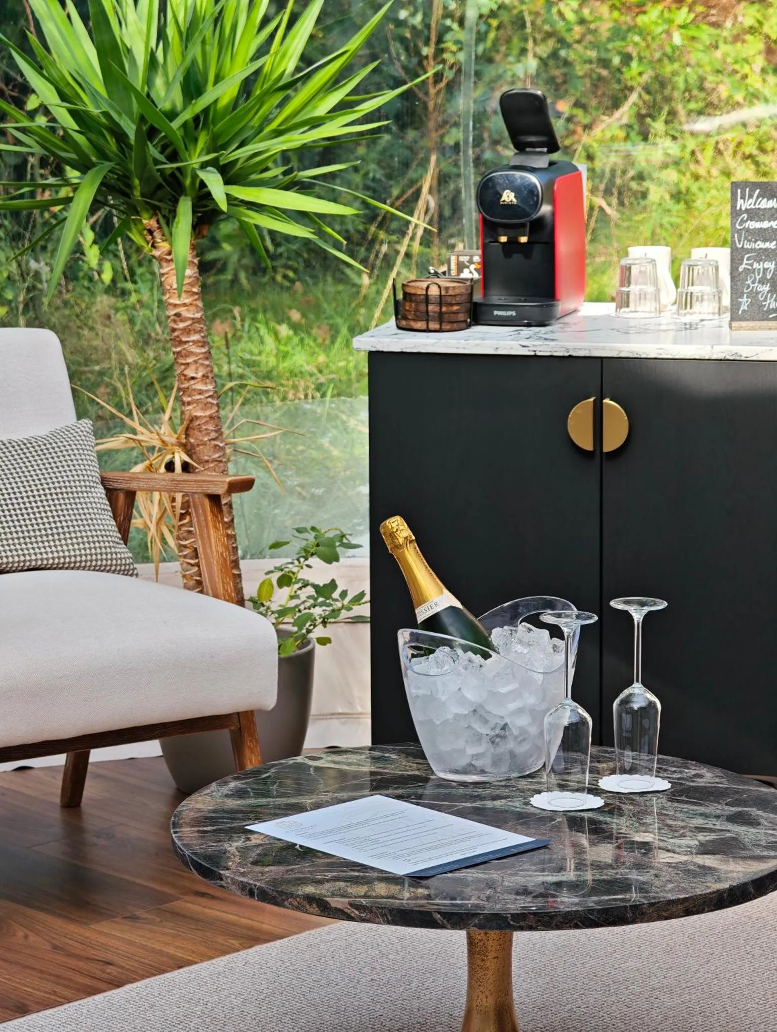 Une table ronde en marbre présente une bouteille de champagne, des verres et une serviette.