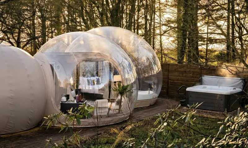 Hébergements insolites en forme de bulle transparente avec lit et mobilier.