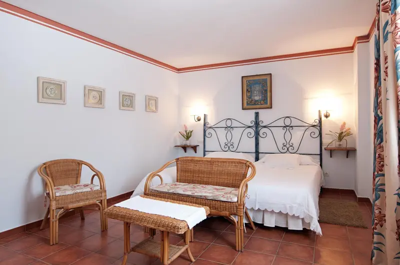 Une chambre lumineuse avec un lit à baldaquin et des meubles en rotin.