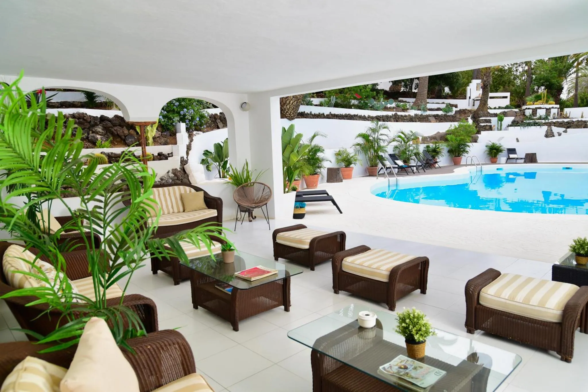 Espace de détente extérieur avec mobilier en rotin et piscine.