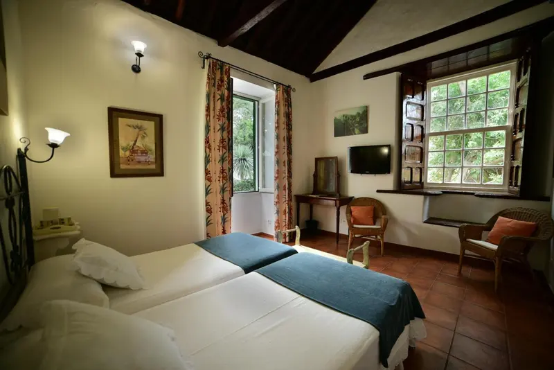 Une chambre lumineuse avec deux lits simples et une vue sur la végétation.