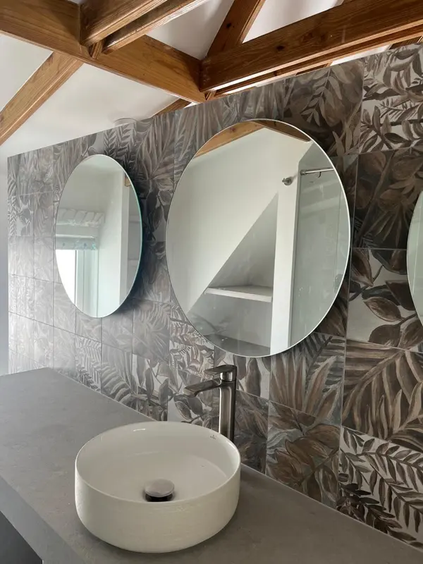 Une salle de bain moderne avec un lavabo blanc et un grand miroir rond.