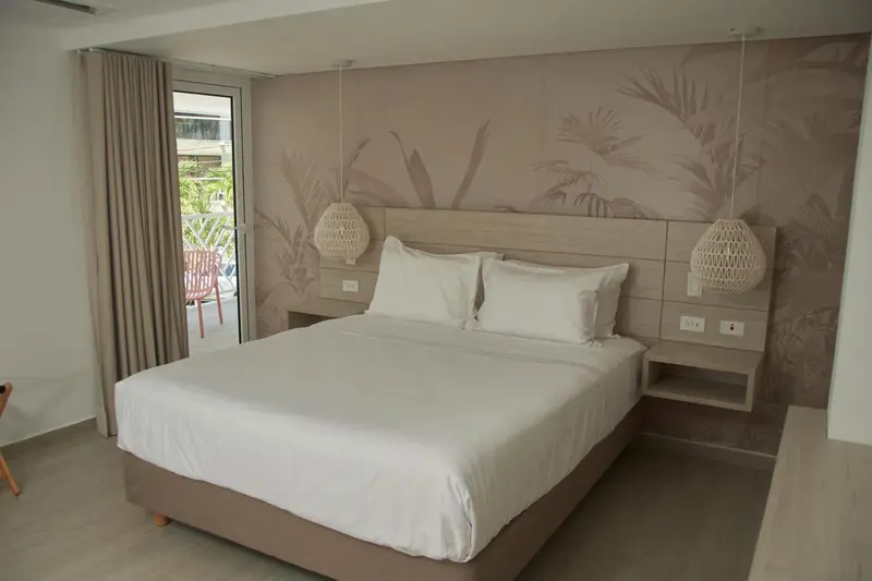 Une chambre lumineuse avec un grand lit et un décor mural tropical.