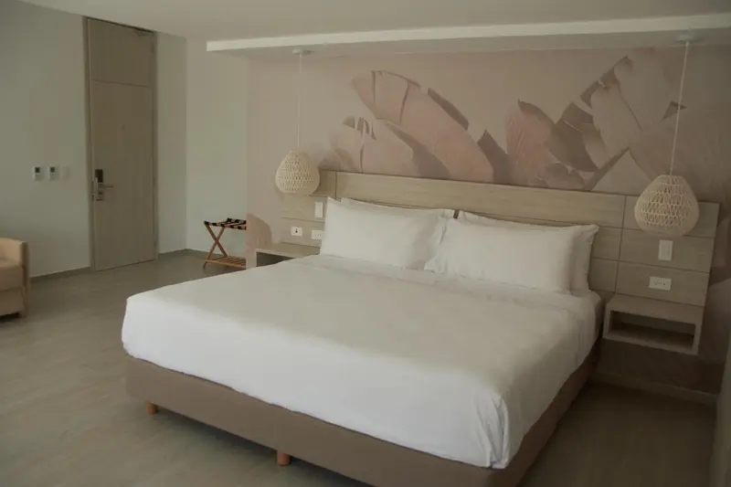 Une chambre lumineuse avec un grand lit recouvert de linge blanc.