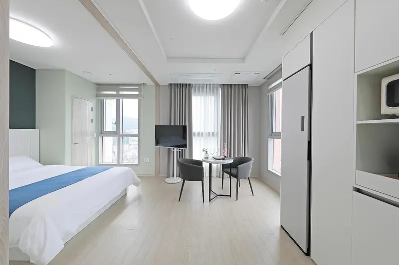 Une chambre lumineuse avec un lit et un coin repas près de la fenêtre.