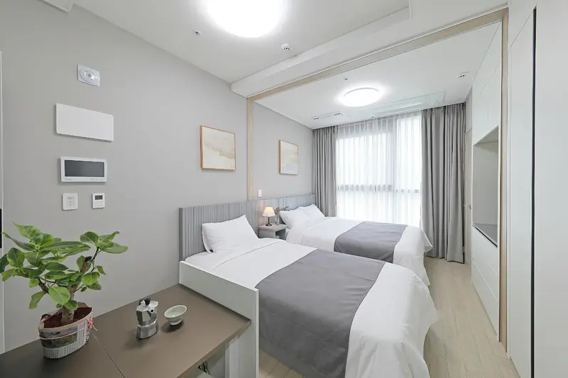 Une chambre lumineuse avec deux lits simples et un grand miroir.