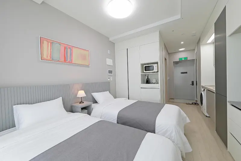Une chambre lumineuse avec deux lits simples et un espace kitchenette.