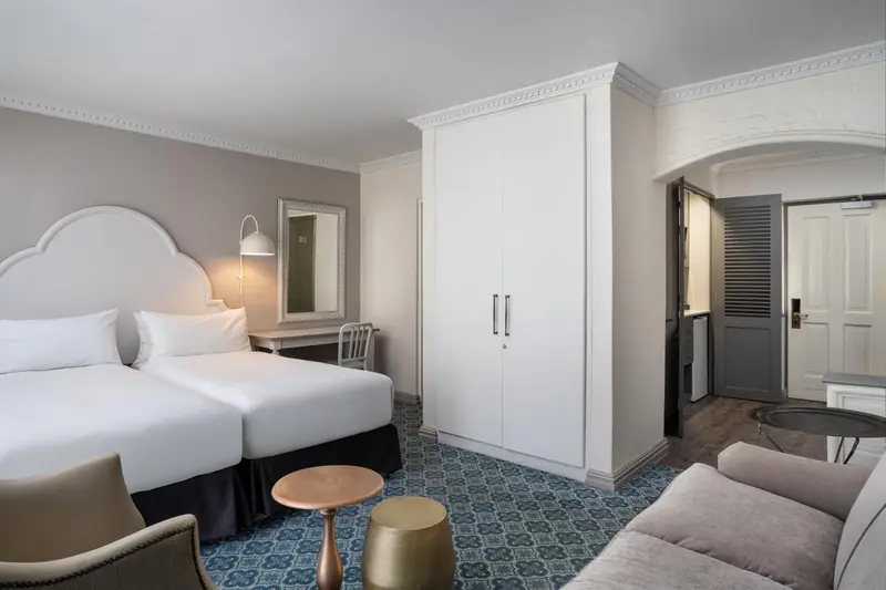 Une chambre lumineuse avec un grand lit et une armoire blanche.