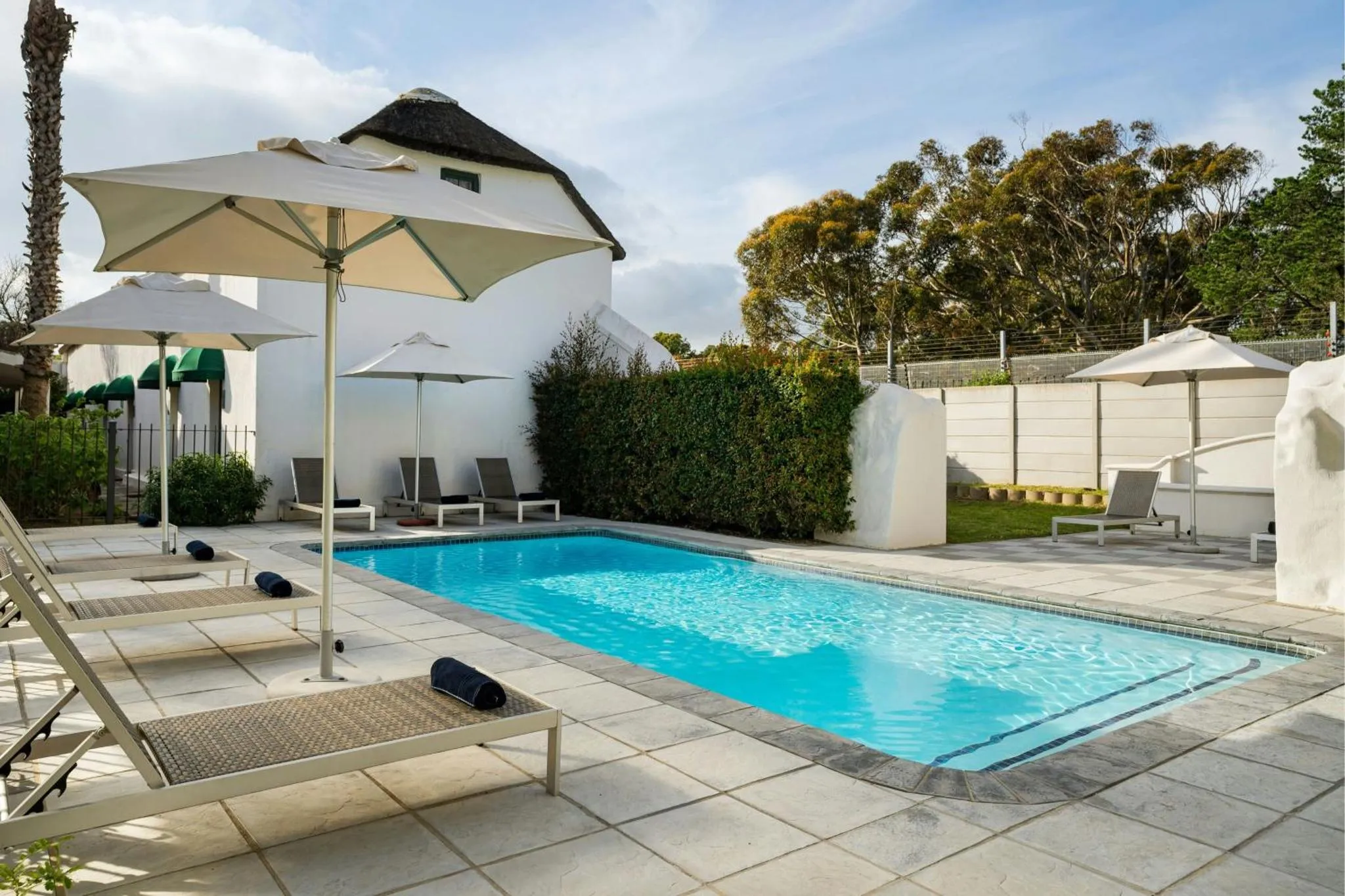 Transats blancs disposés autour d'une piscine rectangulaire carrelée.