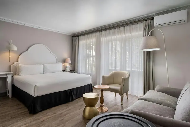 Une chambre lumineuse avec un lit double et un coin salon.