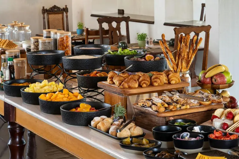 Un buffet propose une variété de pâtisseries, de fruits et de céréales.