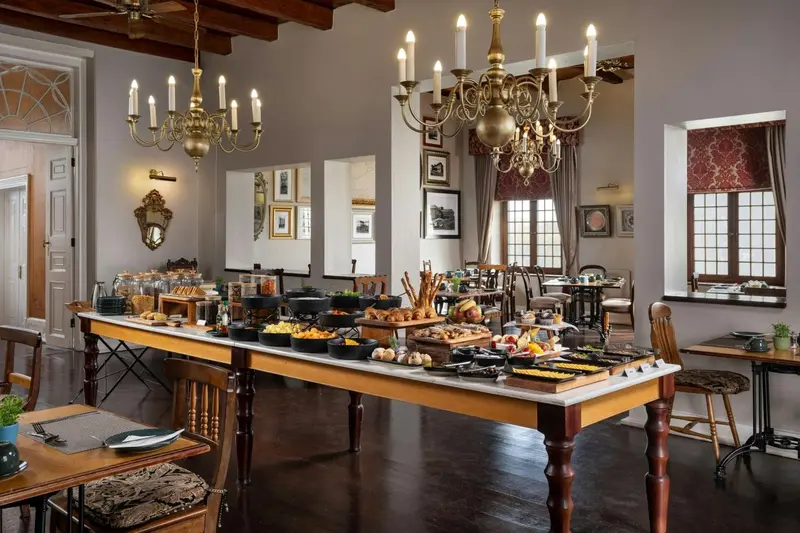 Une longue table en bois est dressée avec un buffet copieux dans une salle à manger élégante.