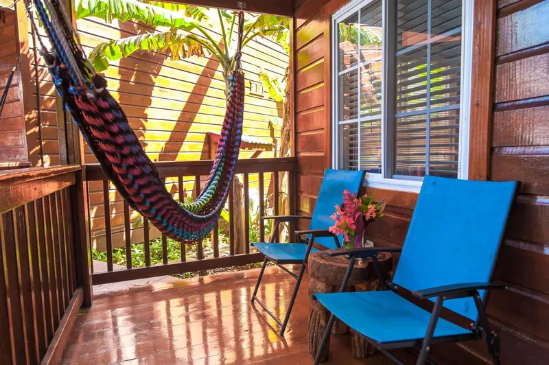Terrasse en bois avec hamac coloré et mobilier de jardin.