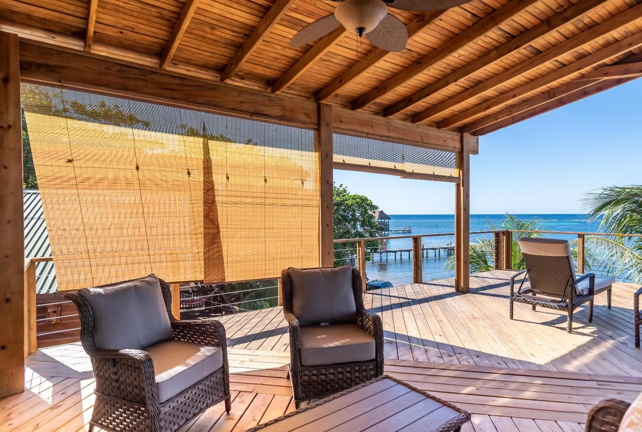 Deux fauteuils confortables invitent à la détente sur une terrasse en bois face à la mer.