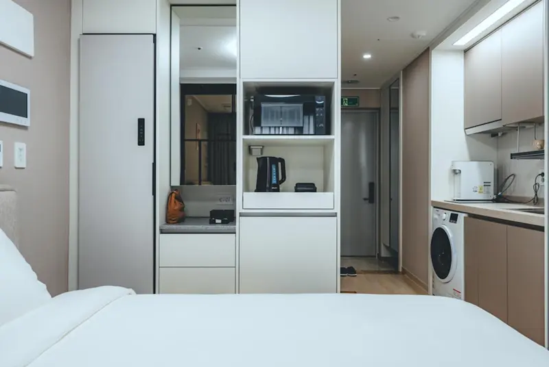 Une kitchenette moderne avec un micro-ondes et un réfrigérateur dans un espace de vie lumineux.