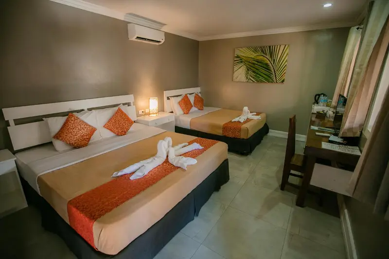 Une chambre avec deux lits décorés de serviettes en forme de cygnes.