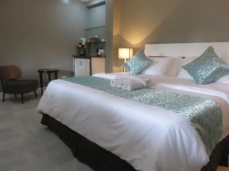 Une chambre lumineuse avec un grand lit et un fauteuil.