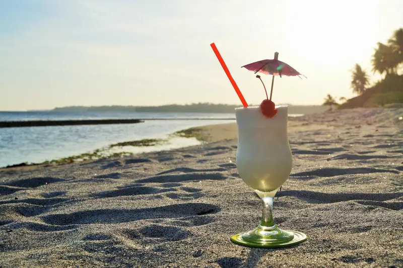 Un cocktail exotique sur une plage de sable au coucher du soleil.