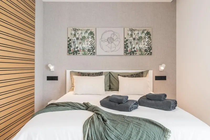 Une chambre lumineuse avec un grand lit recouvert d'une couette et de coussins.