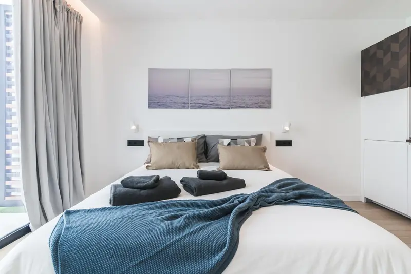 Une chambre lumineuse avec un grand lit recouvert d'une couverture bleue et de coussins.
