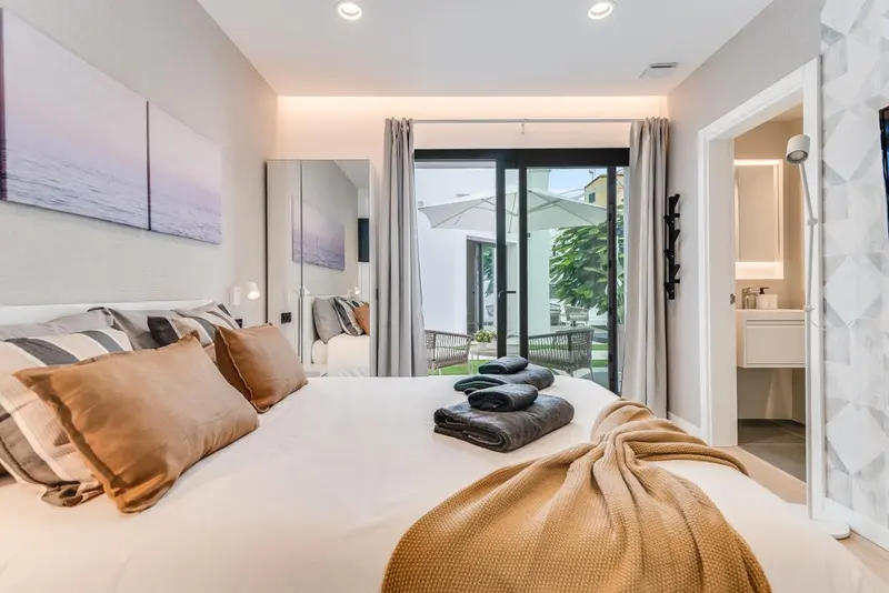 Une chambre lumineuse avec un grand lit et un accès à une terrasse.