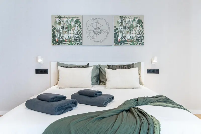 Un lit blanc est dispose dans une chambre aux murs clairs et decorée de tableaux.