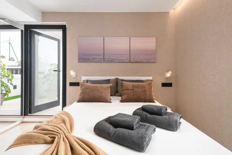 Une chambre lumineuse avec un grand lit et un accès à une terrasse.