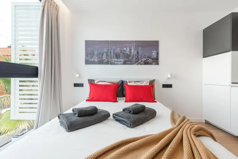 Une chambre lumineuse avec un grand lit recouvert d'une couverture et d'oreillers.