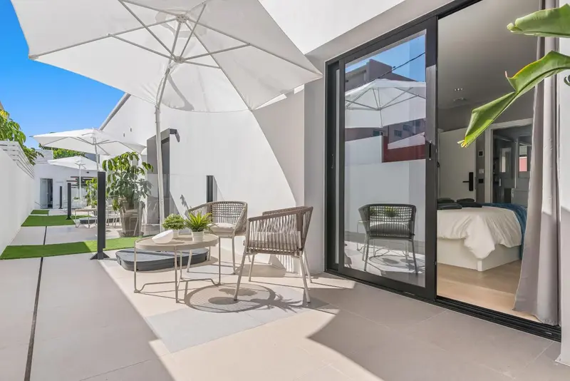 Terrasse aménagée avec mobilier de jardin devant une baie vitrée.