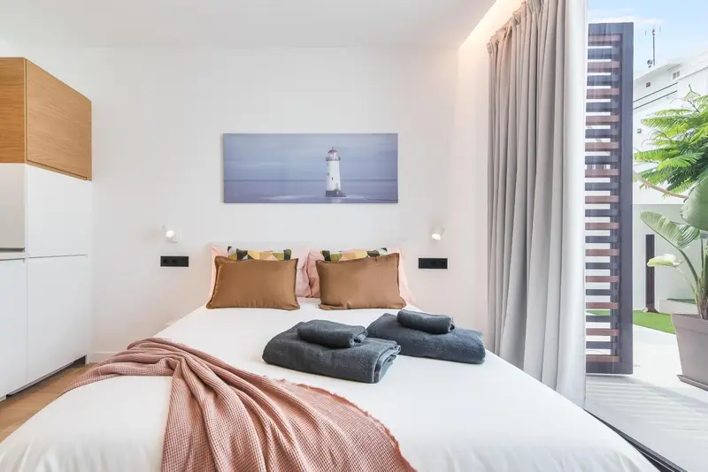 Une chambre lumineuse avec un grand lit recouvert d'une couverture et de coussins.