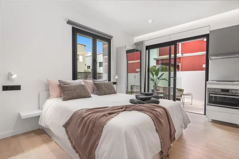 Une chambre lumineuse avec un grand lit et un accès à une terrasse.