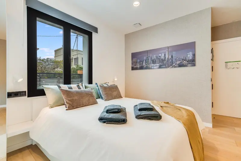 Une chambre lumineuse avec un grand lit recouvert de coussins et de couvertures.