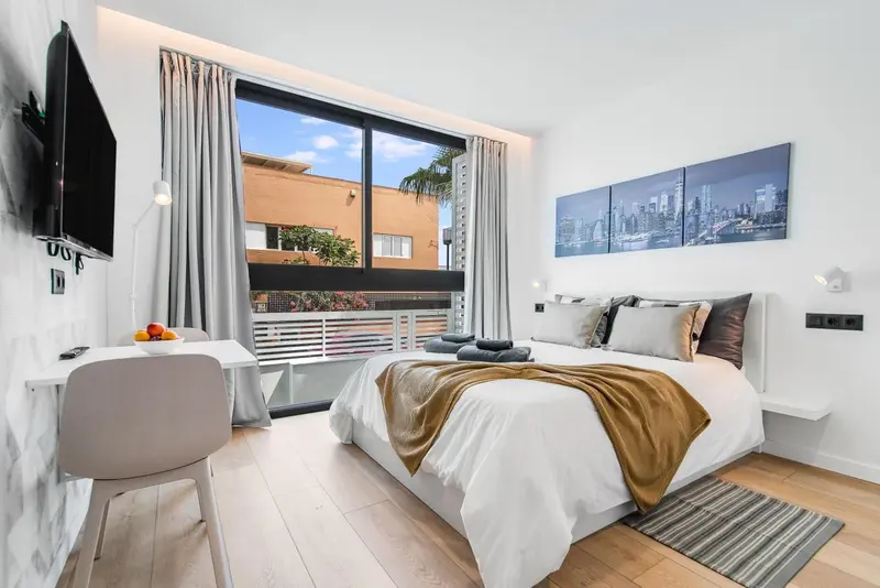 Chambre lumineuse avec un grand lit et une fenêtre donnant sur l'extérieur.