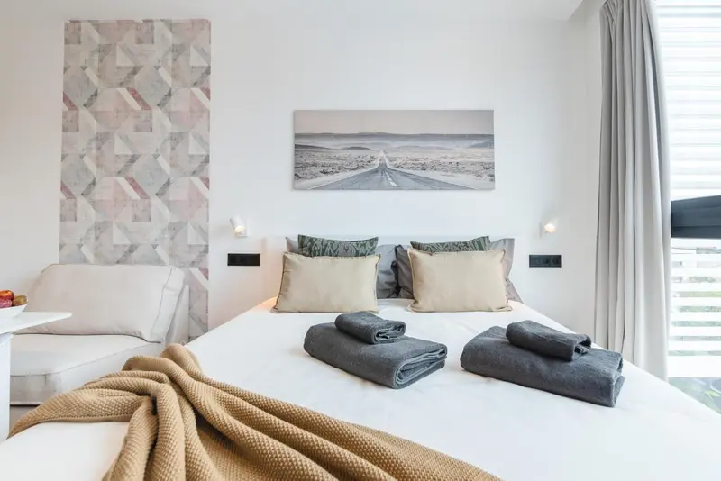 Une chambre lumineuse avec un grand lit et une décoration murale.