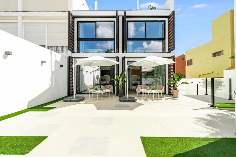 Terrasse aménagée avec mobilier de jardin et parasols devant des logements modernes.