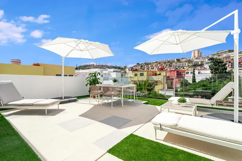 Terrasse aménagée avec mobilier de détente et vue sur la ville.