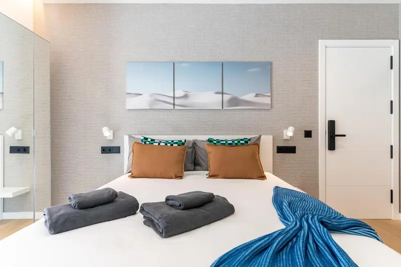 Une chambre lumineuse avec un grand lit recouvert de coussins et de couvertures.