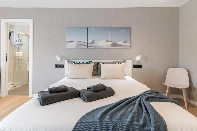 Une chambre lumineuse avec un grand lit recouvert d'une couverture et de coussins.