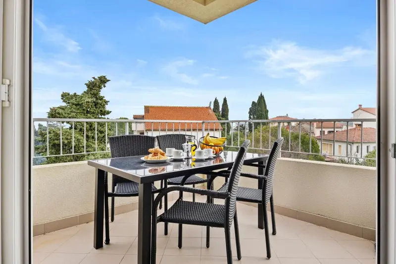 Une table de repas est mise en scène sur une terrasse avec vue sur un paysage urbain.