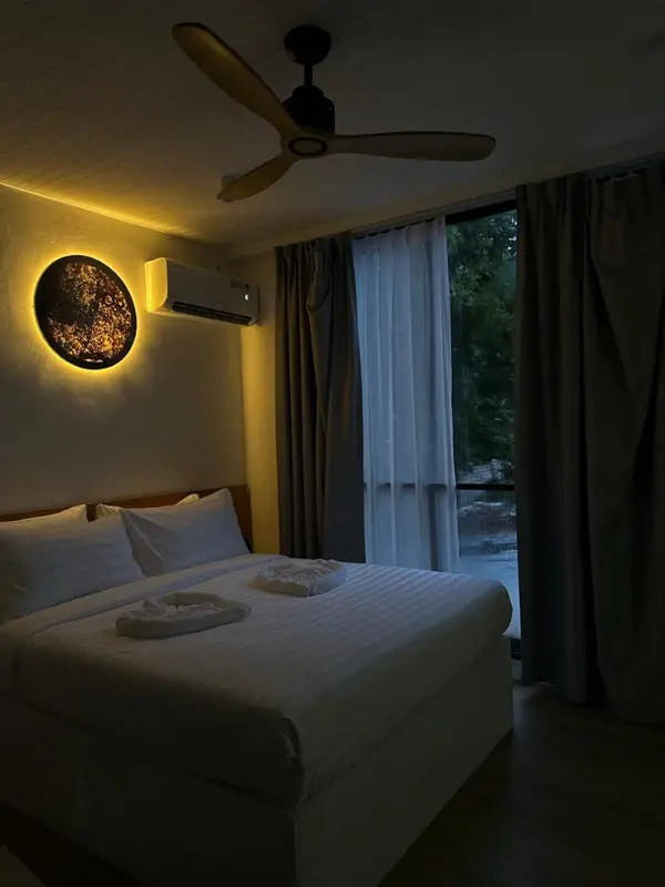 Une chambre lumineuse avec un grand lit et un ventilateur au plafond.