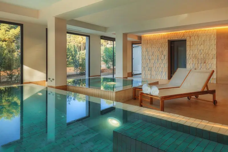 Espace de détente intérieur avec piscine et chaises longues.