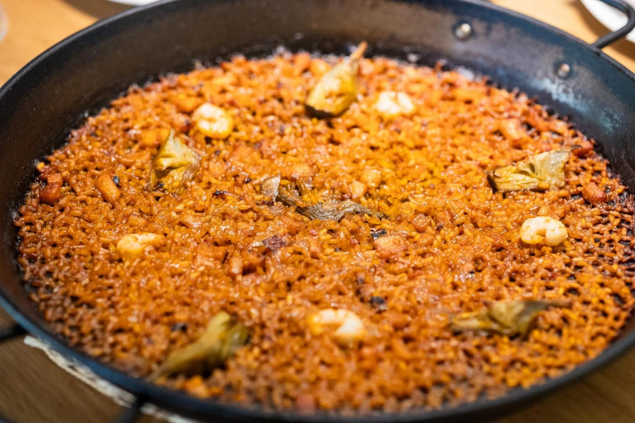 Une grande poêle de paella aux fruits de mer est présentée de près.