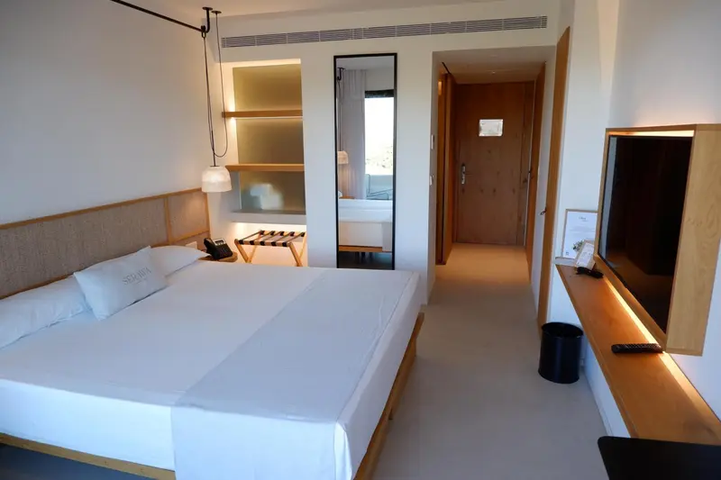Une chambre lumineuse avec un grand lit et un téléviseur mural.